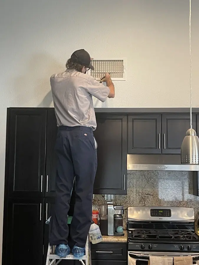 Technician inspecting an air vent during HVAC service in Winslow